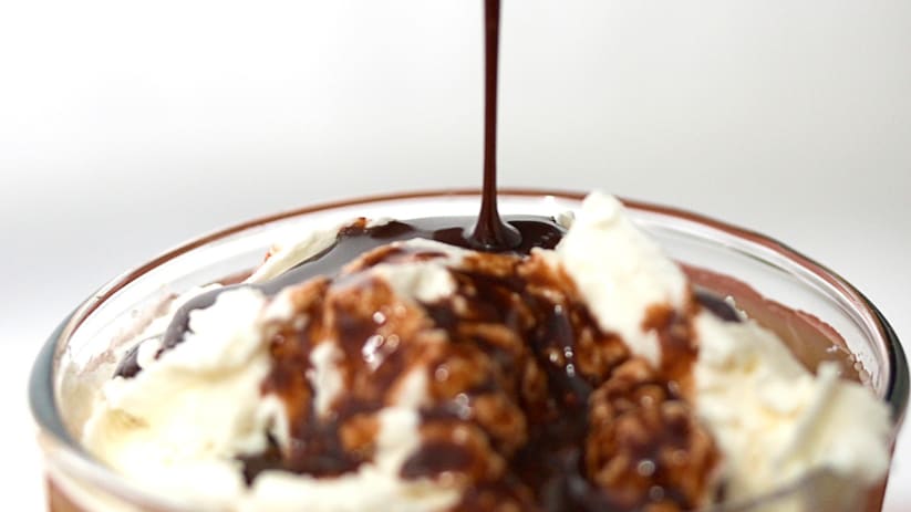 Homemade Hershey's chocolate syrup drizzling over a chocolate drink with whipped cream