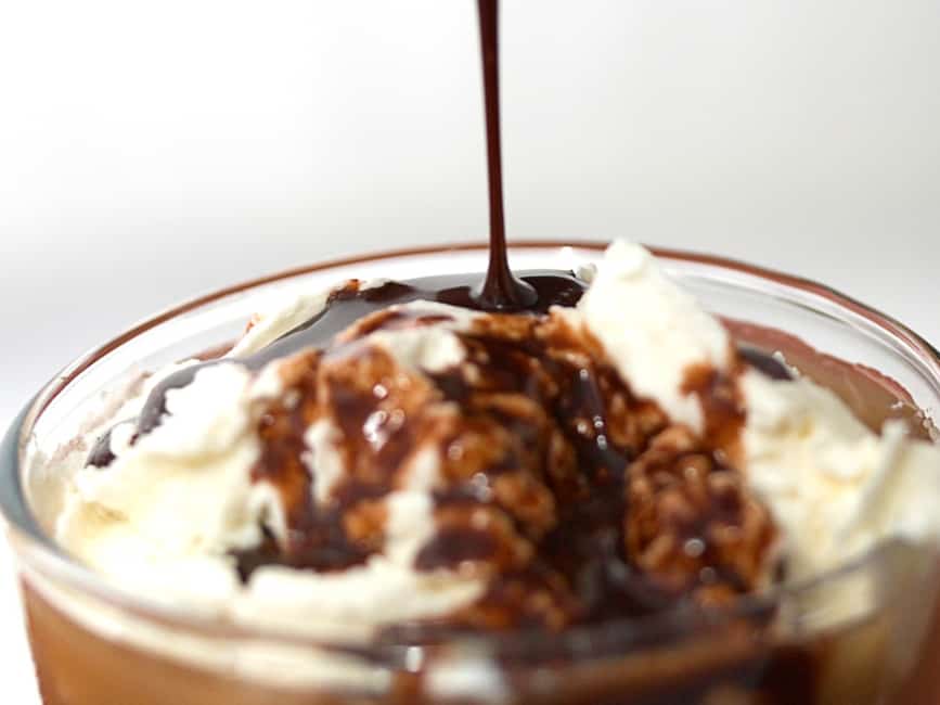 Homemade Hershey's syrup pouring into a drink with whipped cream