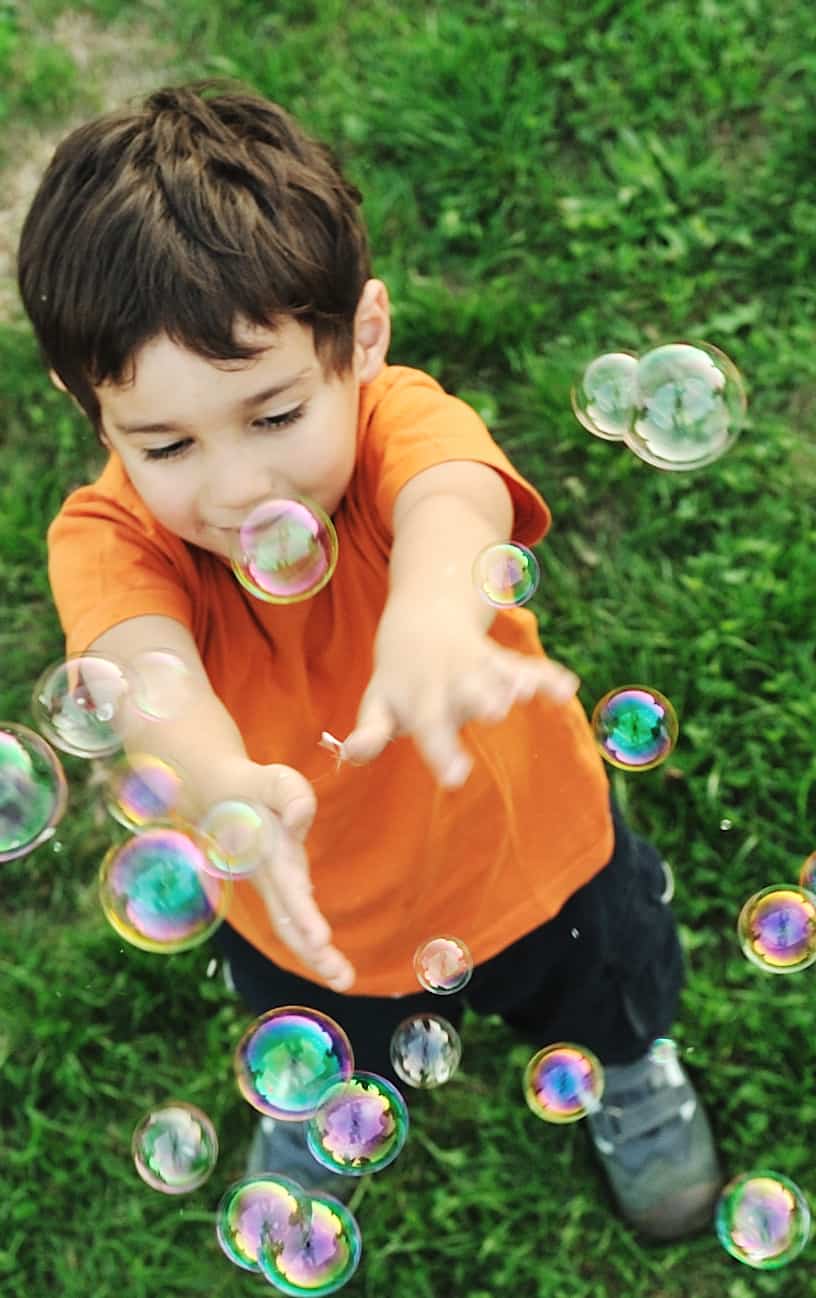 bubble recipe and an overhead view of boy in orange shirt reaching up towards bubbles floating in front of him.