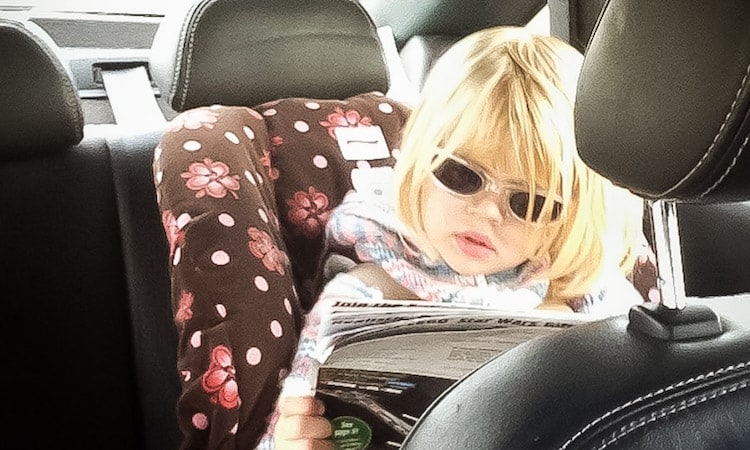 toddler girl in backseat reading a magazine on a road trip