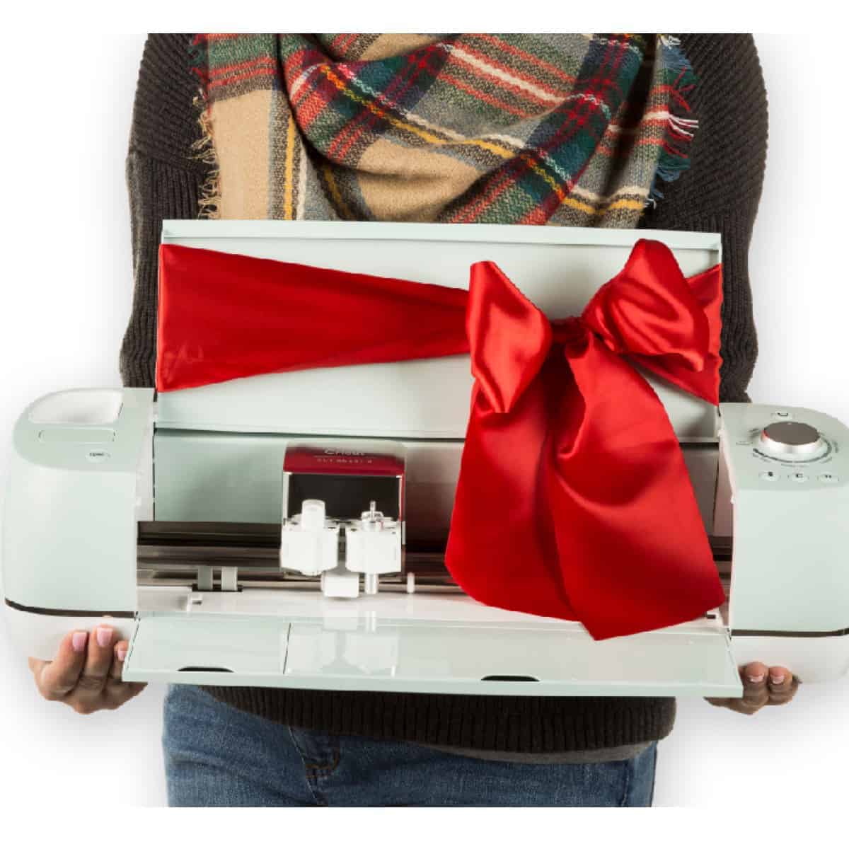 Woman in scarf holding a Mint green Cricut Explore air 2 with a red bow tied around it