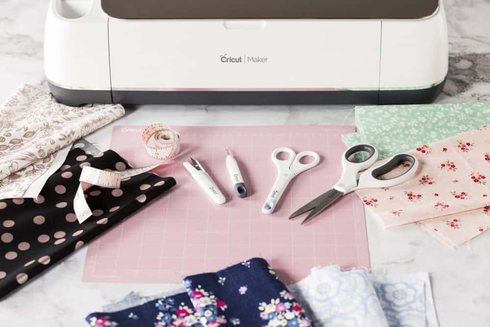 Scissrs, quill, tweezers and sewing supplies in front of a Cricut Maker 