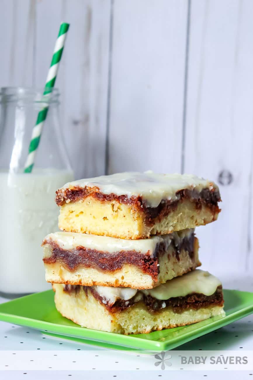 3 stacked dessert bars on a green plate with a bottle of milk in the background