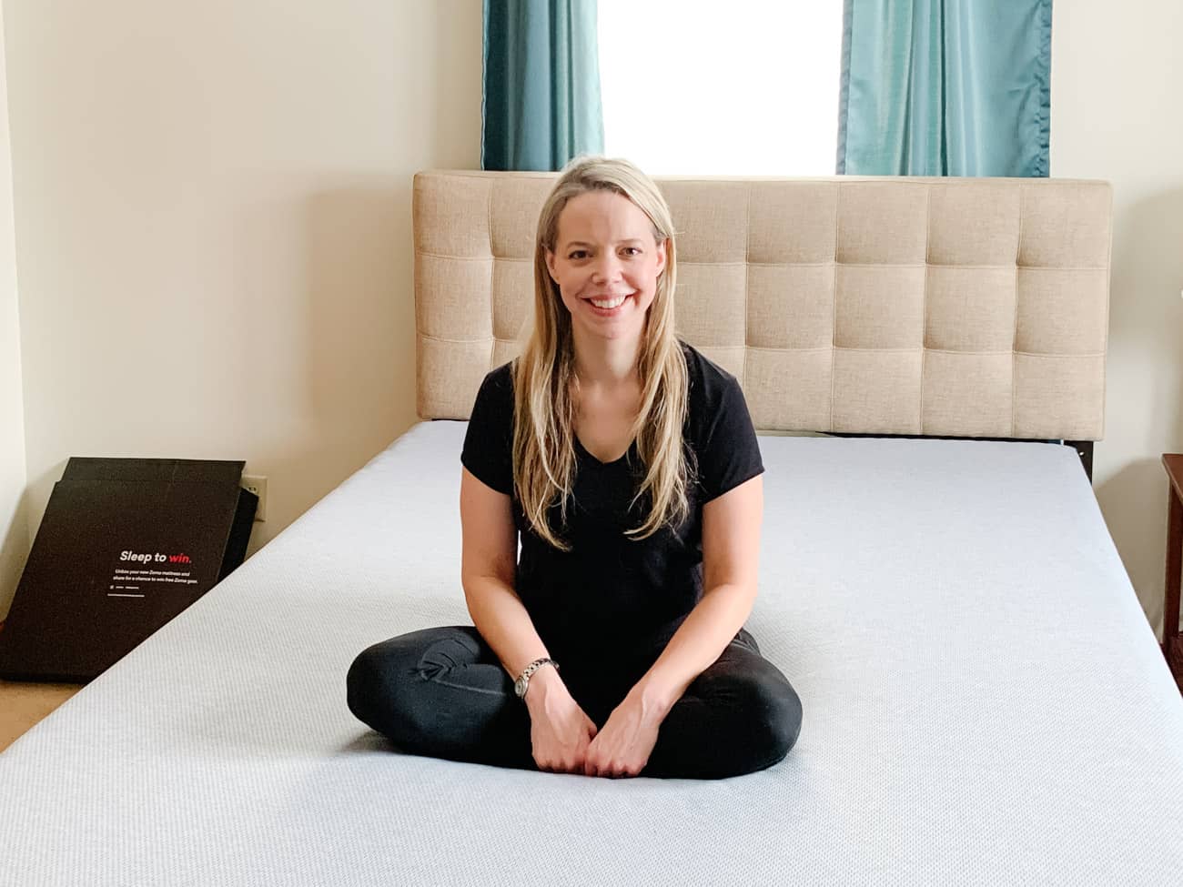 smiling woman sitting on a zoma mattress