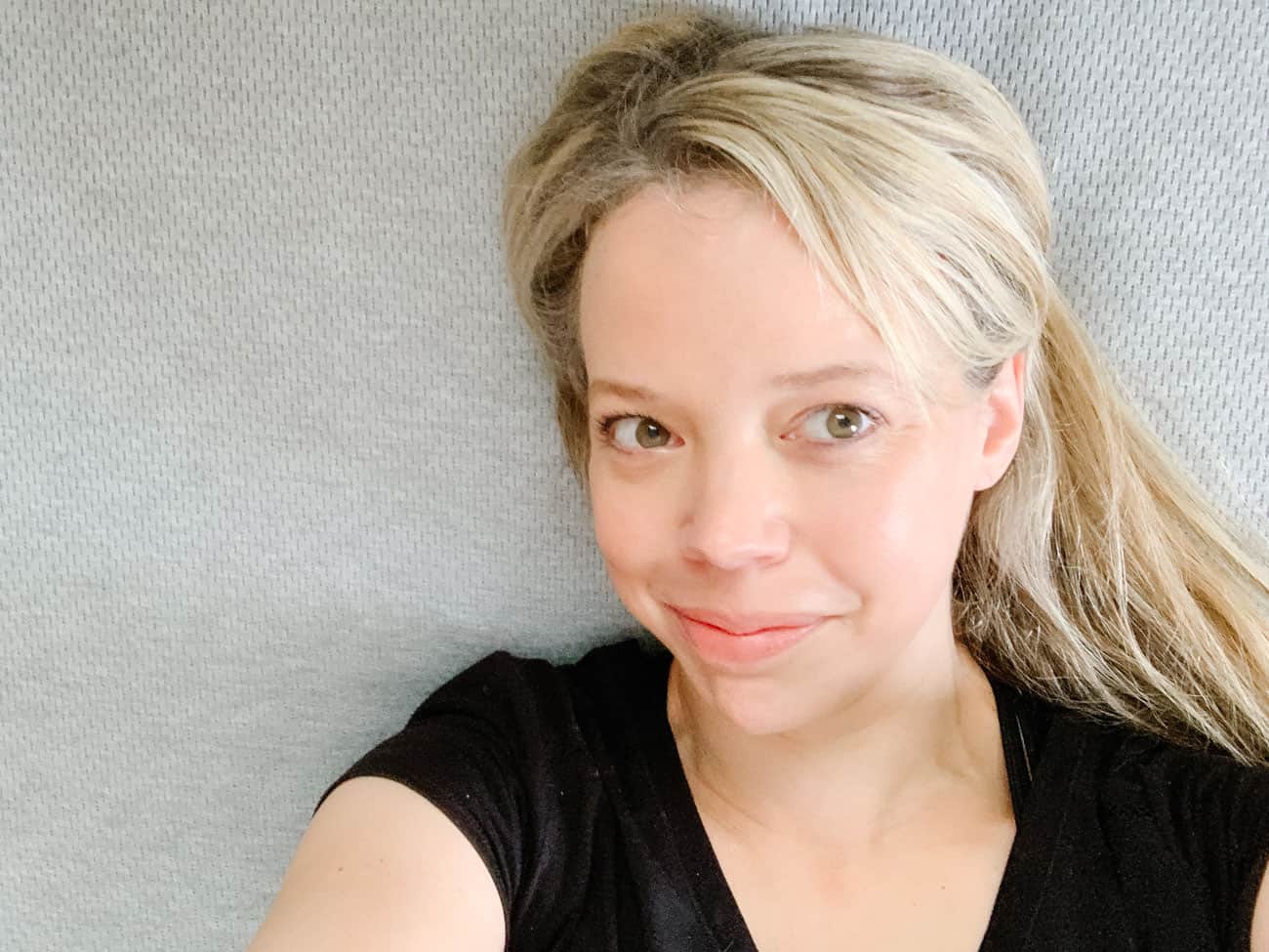 overhead view of smiling woman laying on new mattress