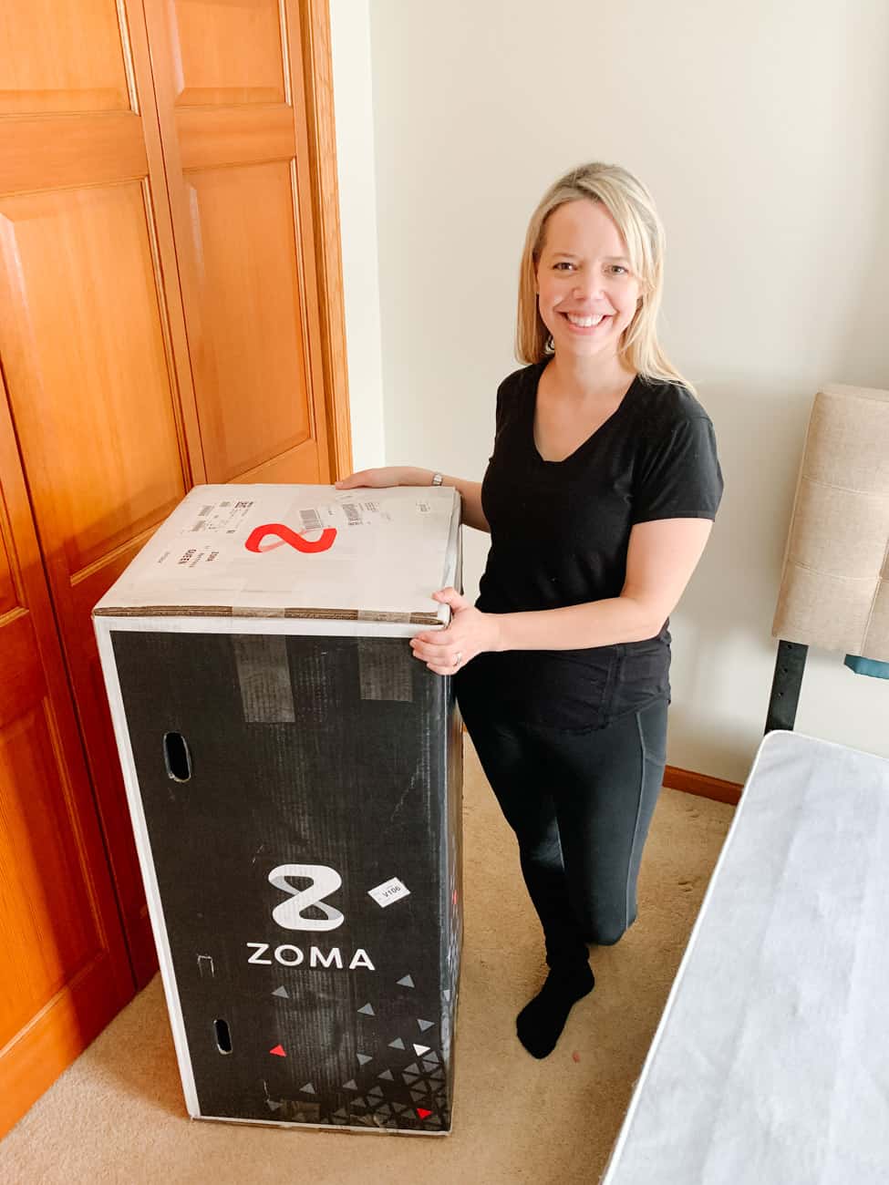 Zoma mattress bed in a box next to a smiling woman