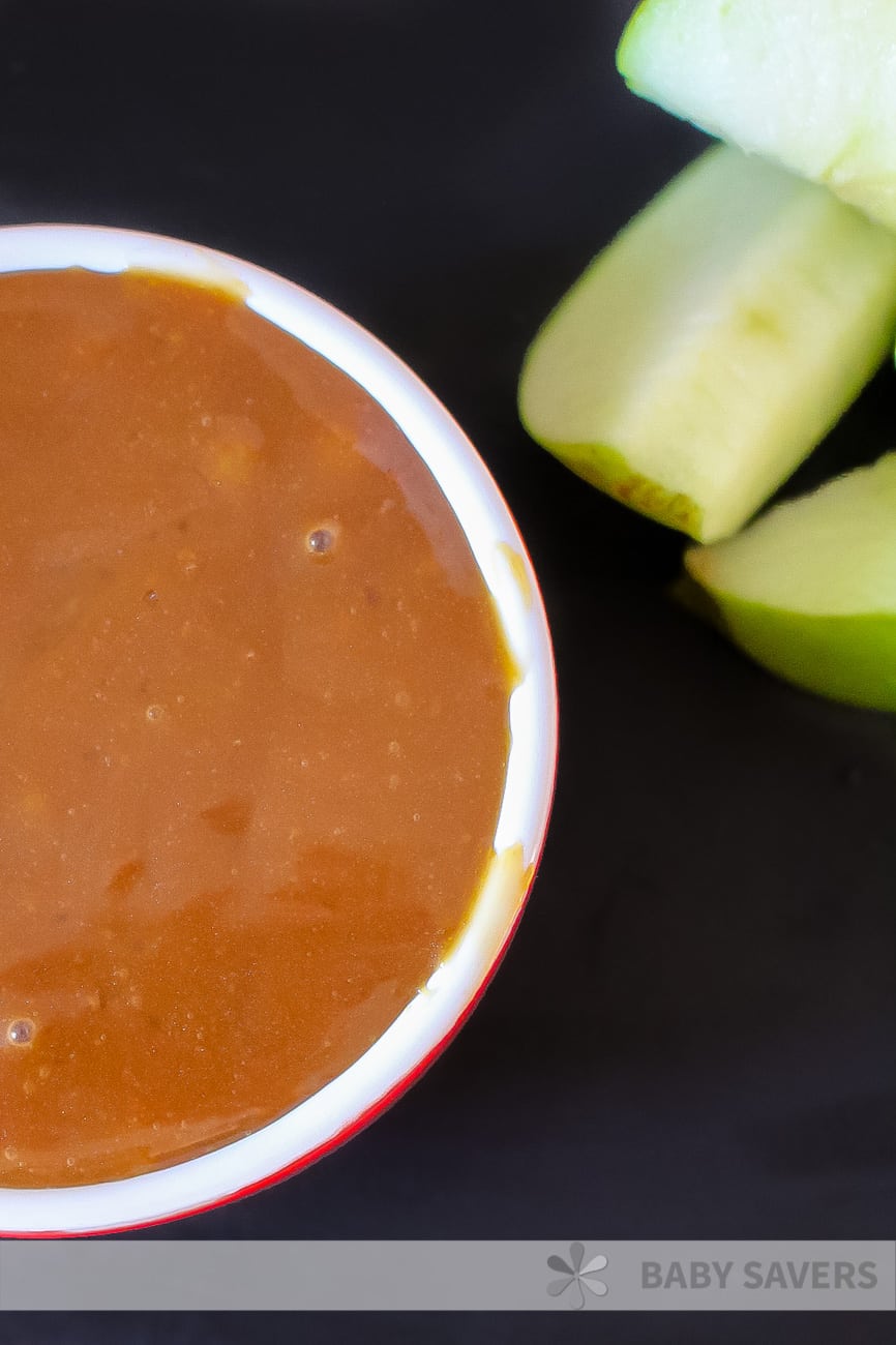 Caramel sauce in red dish on black background