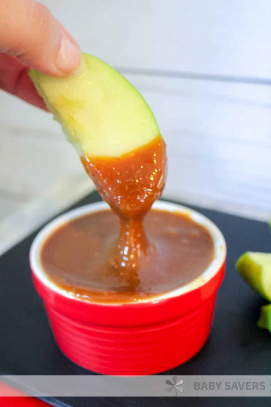 Dipping apple in caramel sauce made in slow cooker