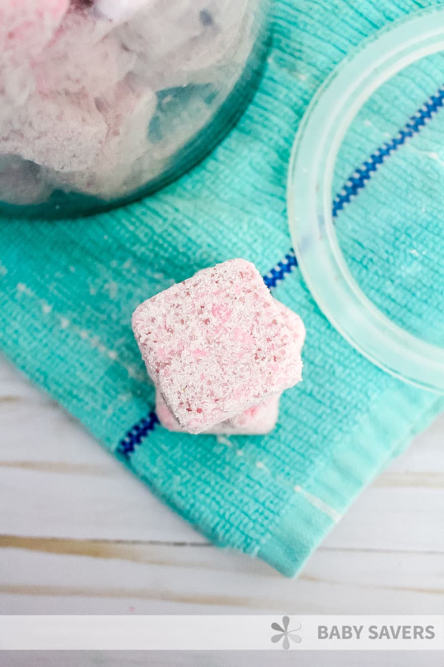 pink square of DIY laundry soap on a green kitchen towel next to glass jar