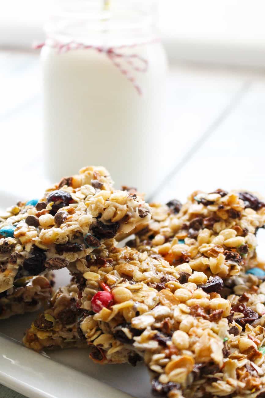Crunchy granola bars stacked on a plate with a glass of milk in the background