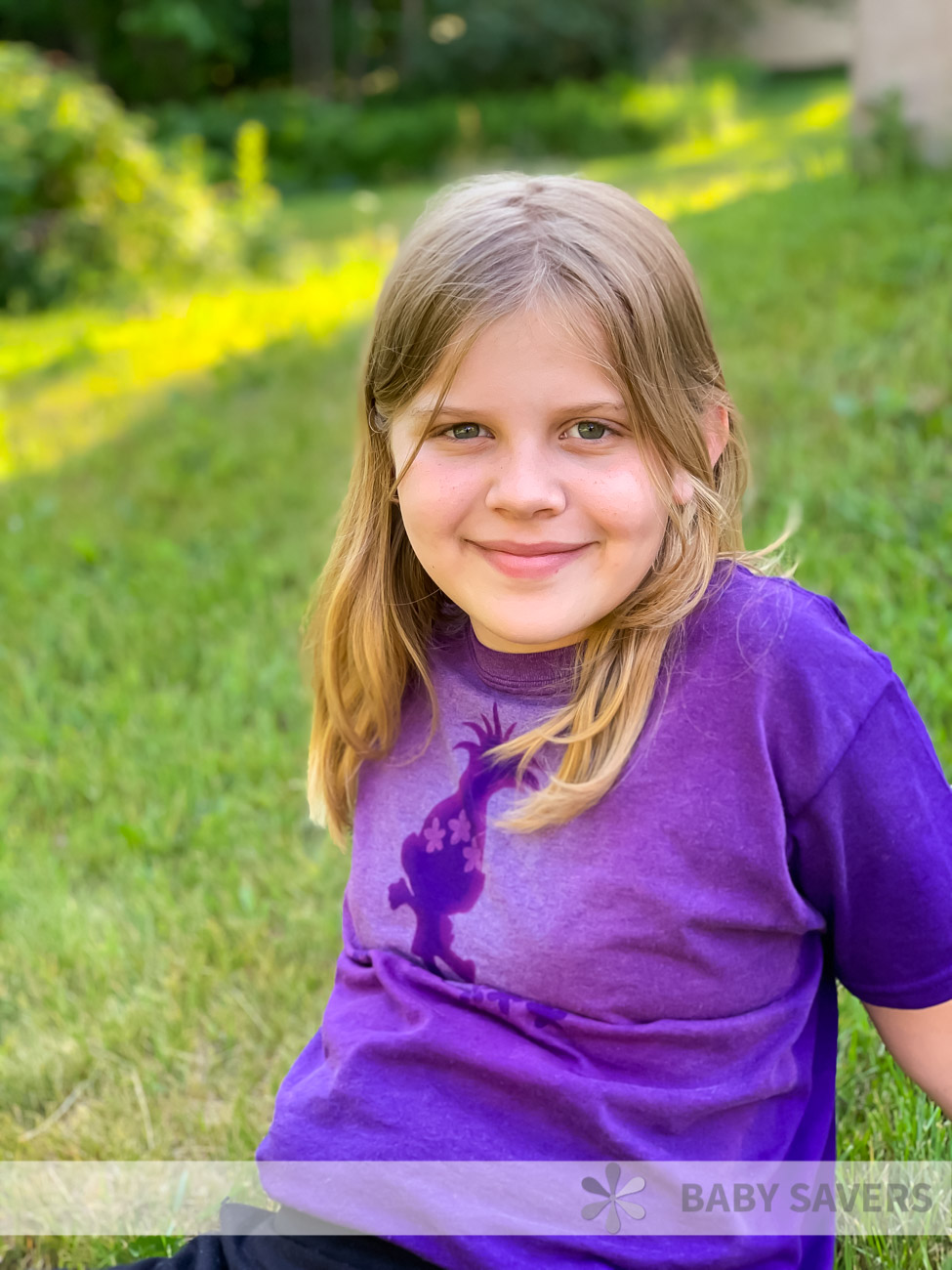 smiling girl wearing a purple shirt with trolls