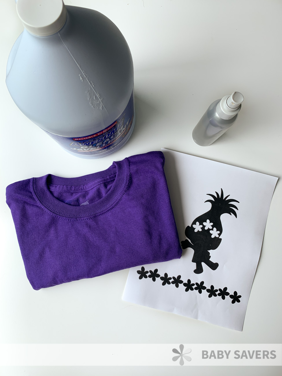 Bottle of bleach, spray bottle, purple t shirt and a printed silhouette of Poppy the troll