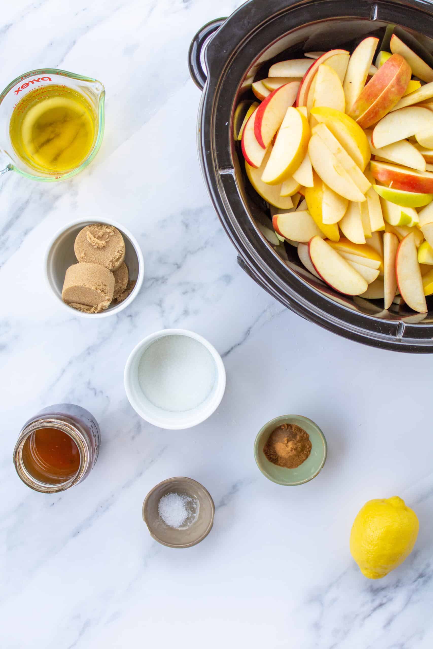 ingredients for apple butter next to a slow cooker filled with sliced apples