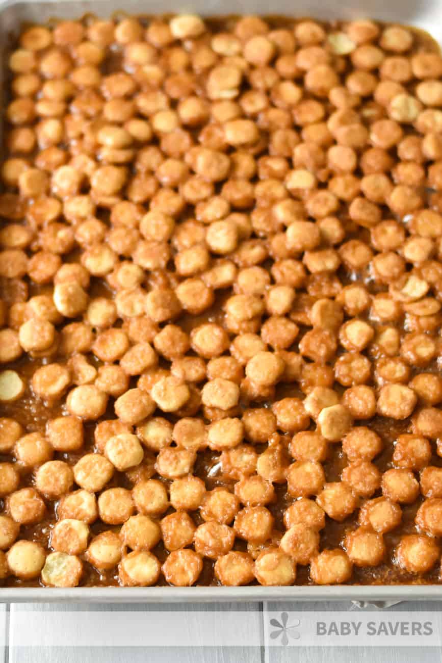 baked oyster crackers on a cookie sheet covered in bubbly caramel syrup while making oyster cracker snack mix 