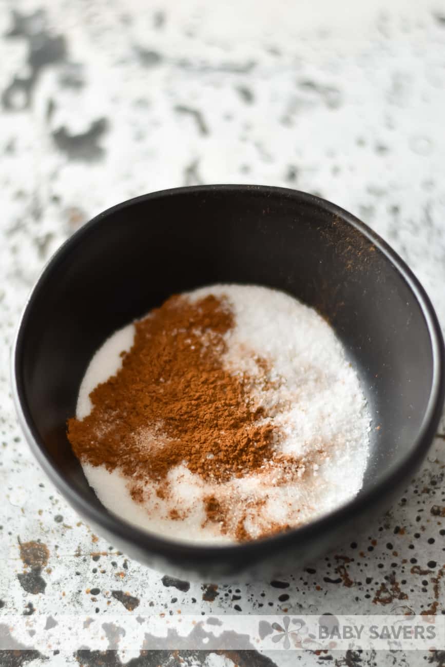 black bowl with cinnamon and sugar to sprinkle on oyster cracker snack mix 