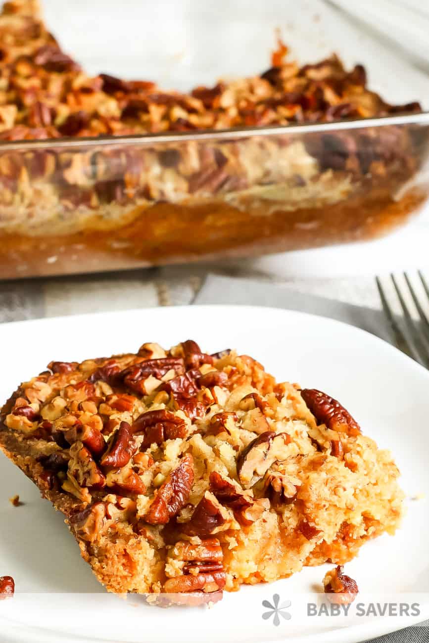 pumpkin crisp on a white plate with a baking dish behind it