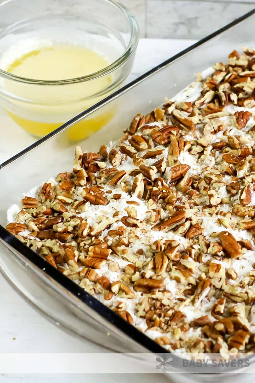 baking dish with unbaked pumpkin pecan crisp and a dish of melted butter on the side