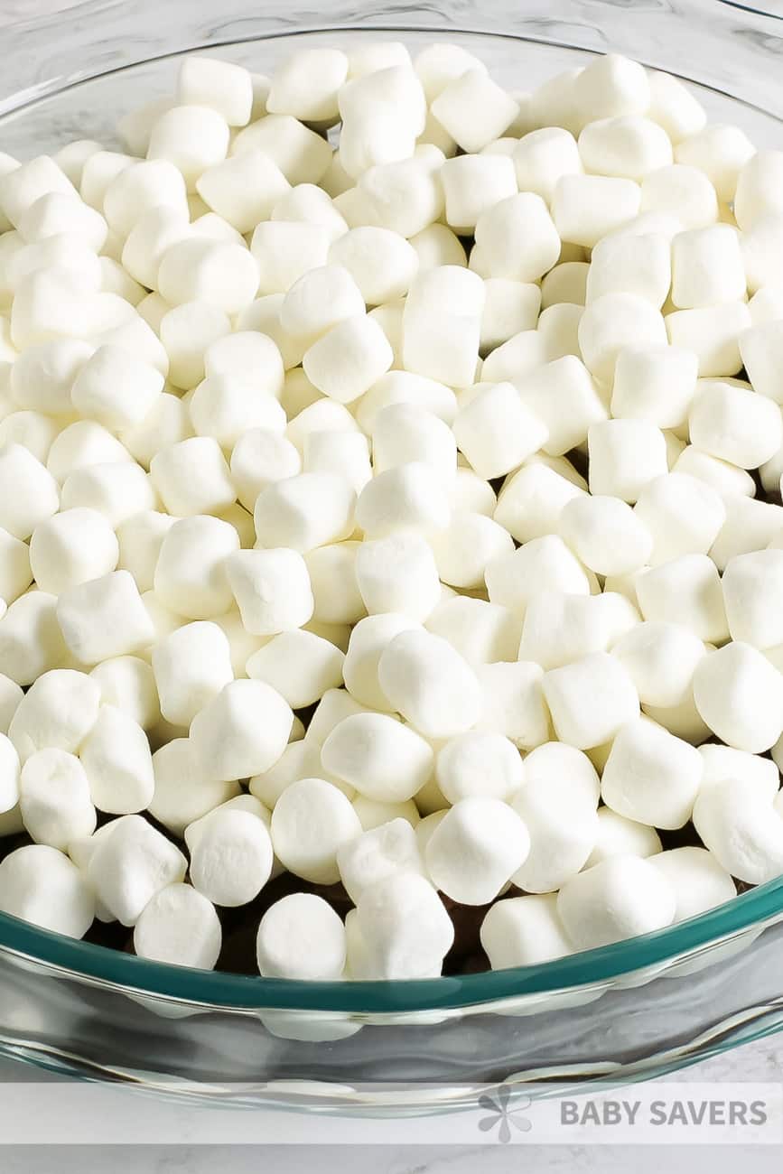 miniature marshmallows over milk chocolate chips in a clear baking dish