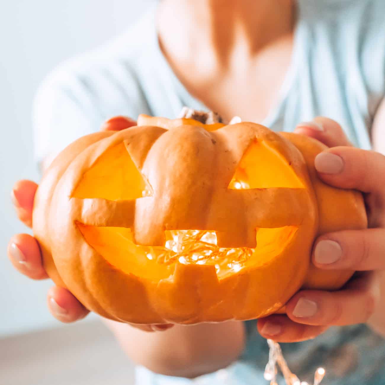 hands holding carved pumpkin for Halloween plus a Halloween word search