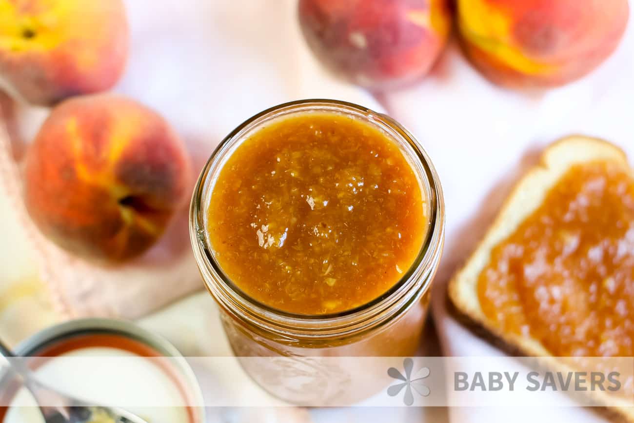 Overhead view of peach butter in jar with fresh peaches