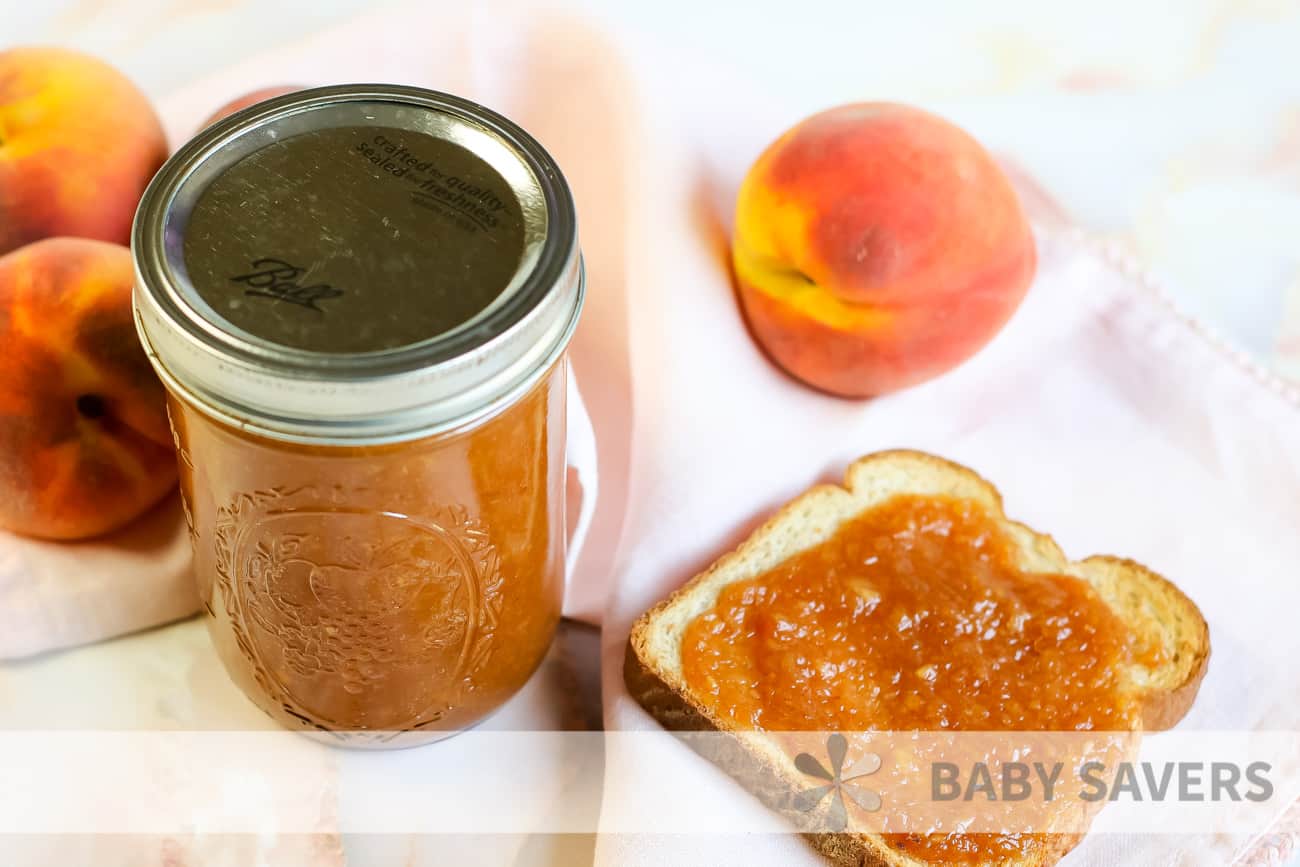 canned peach butter with a piece of toast and fresh peaches