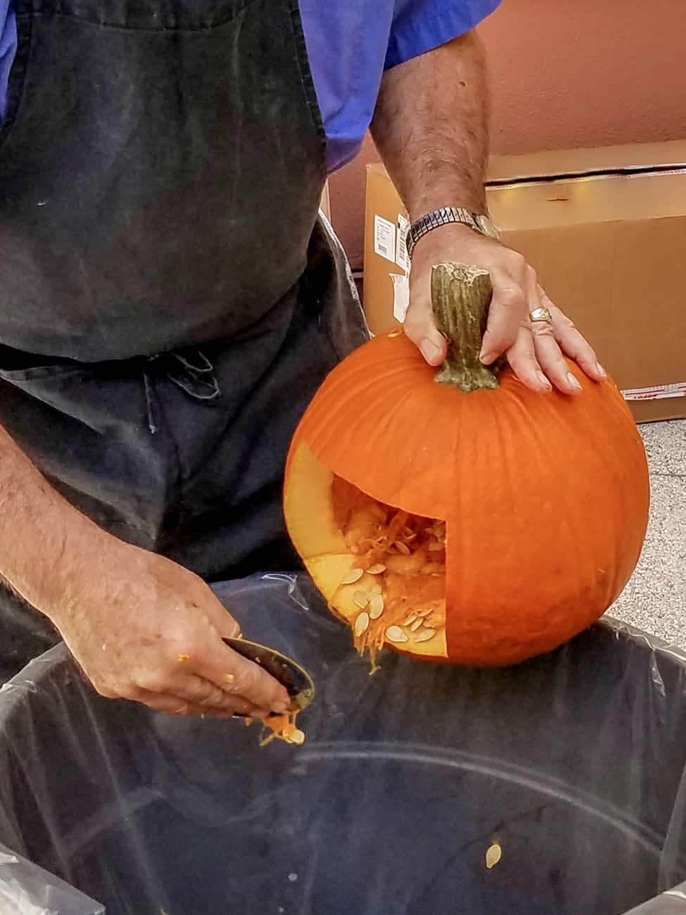 before using the Loki pumpkin stencil, man cleaning out seeds from a pumpkin