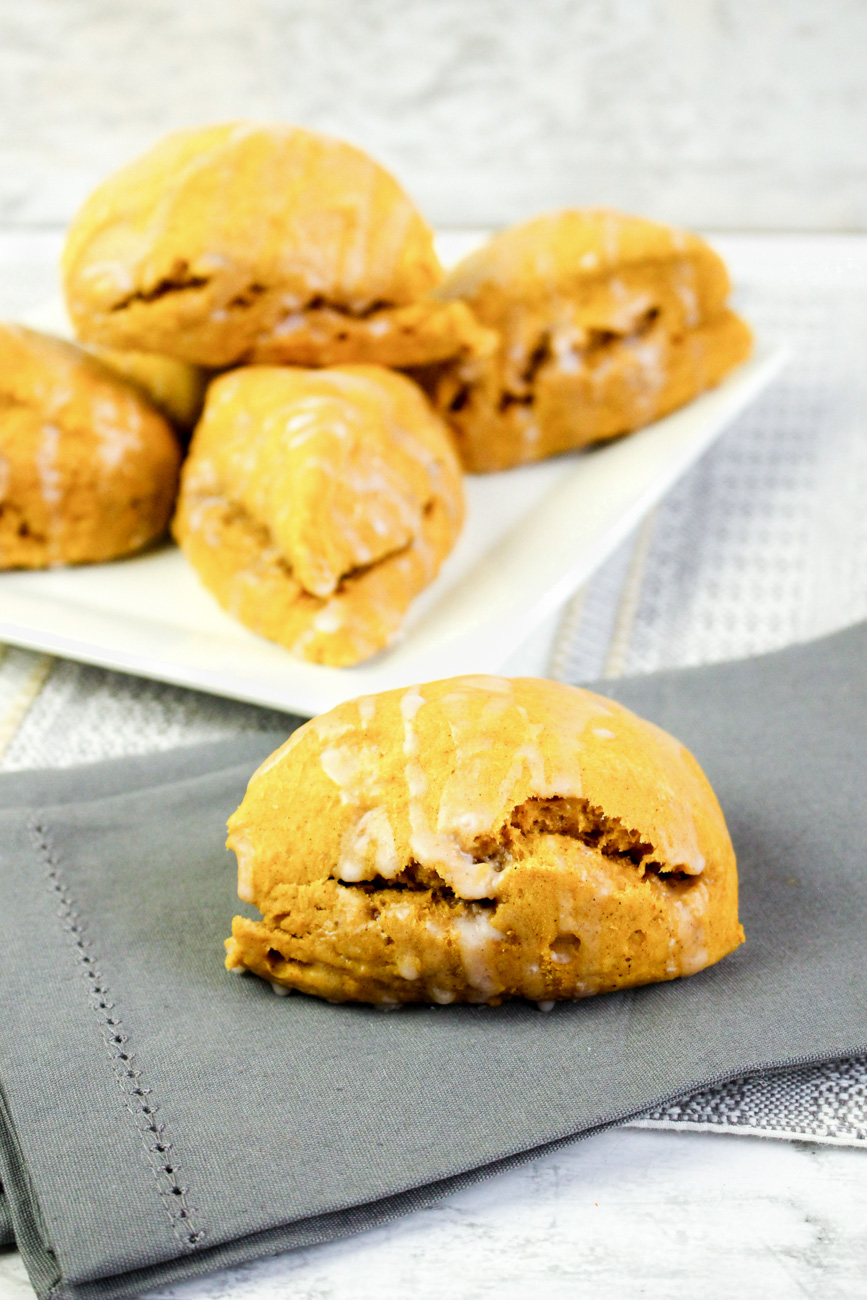 pumpkin scone recipe with scone with icing sitting on a grey napkin