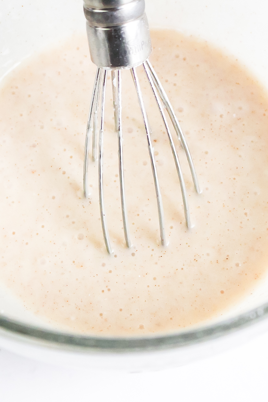 pumpkin scone recipe icing in a bowl with metal wire whisk