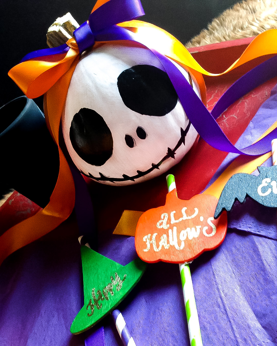 Jack Skellington painted pumpkin with orange and purple ribbons tied around the stem