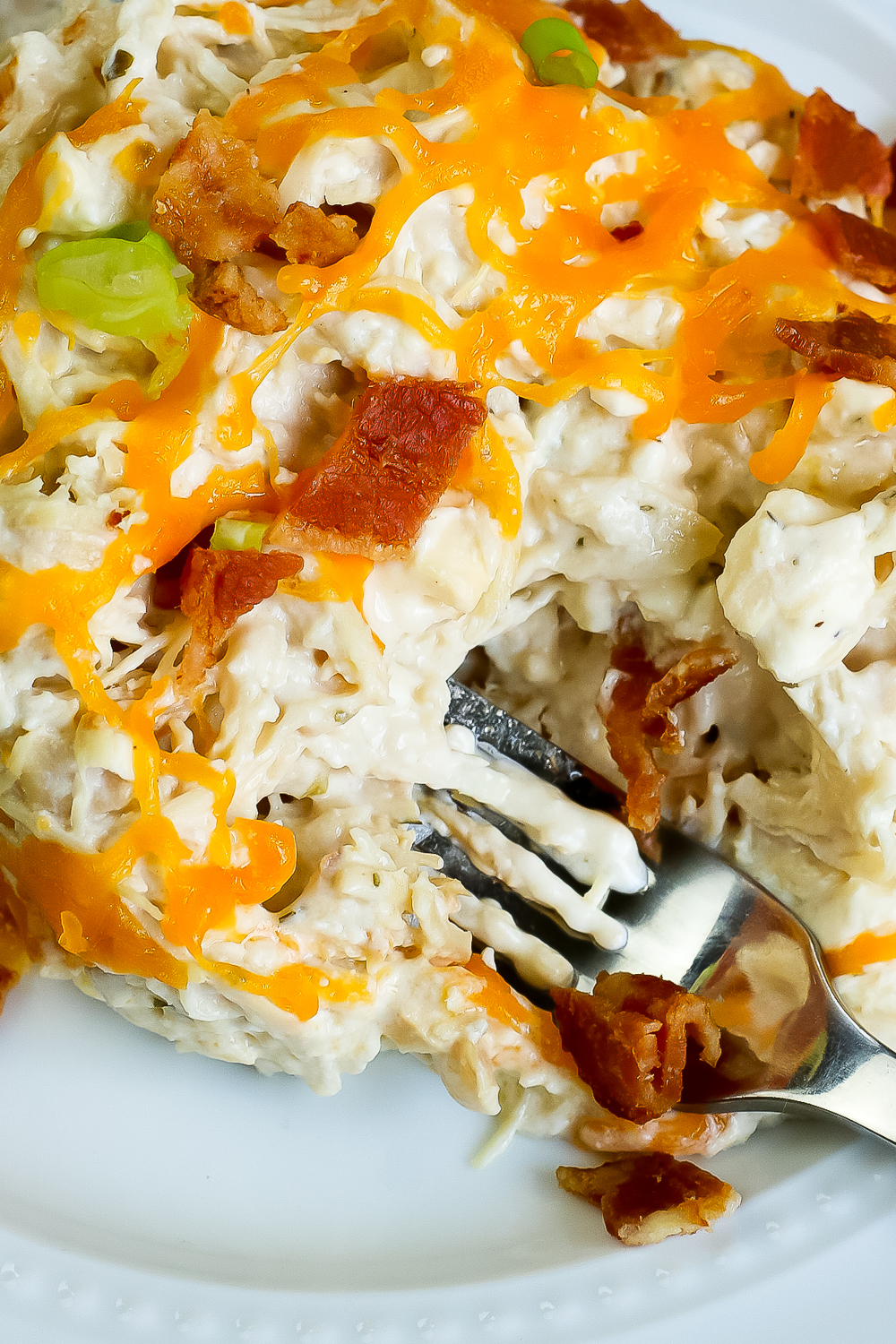 creamy crockpot chicken with a fork and crisp bacon