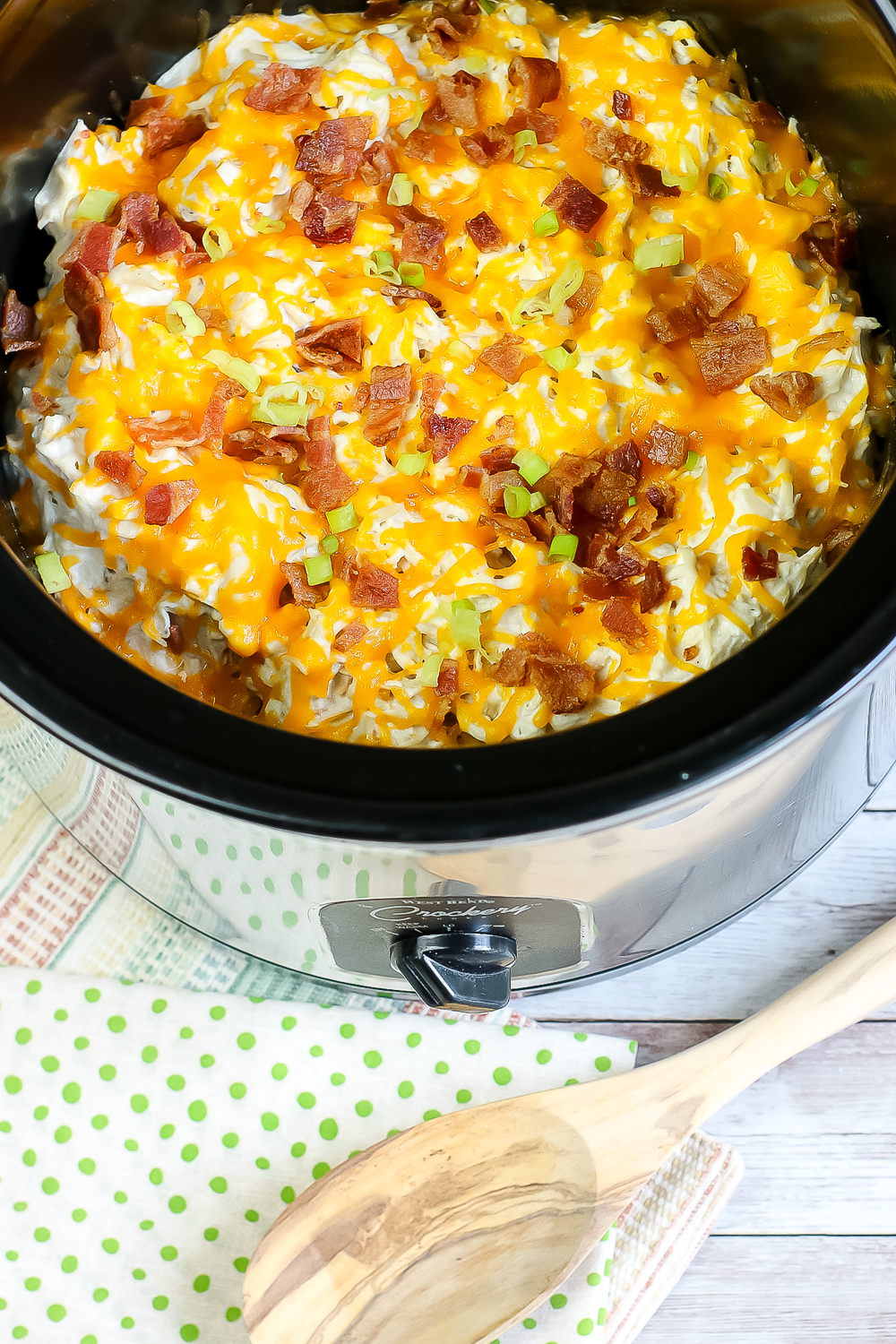 creamy crockpot chicken in slow cooker bowl with crumbled crisp bacon, melted cheese, cream cheese and sliced green onions