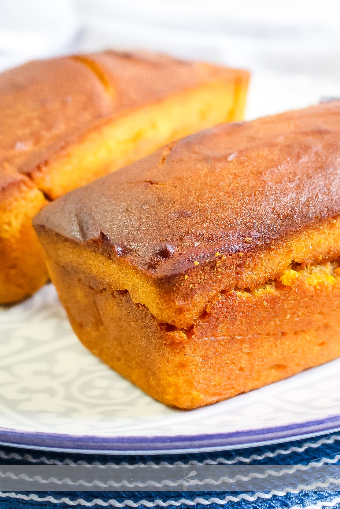 air fryer pumpkin bread two loaves of golden bread on a woven blue placemat