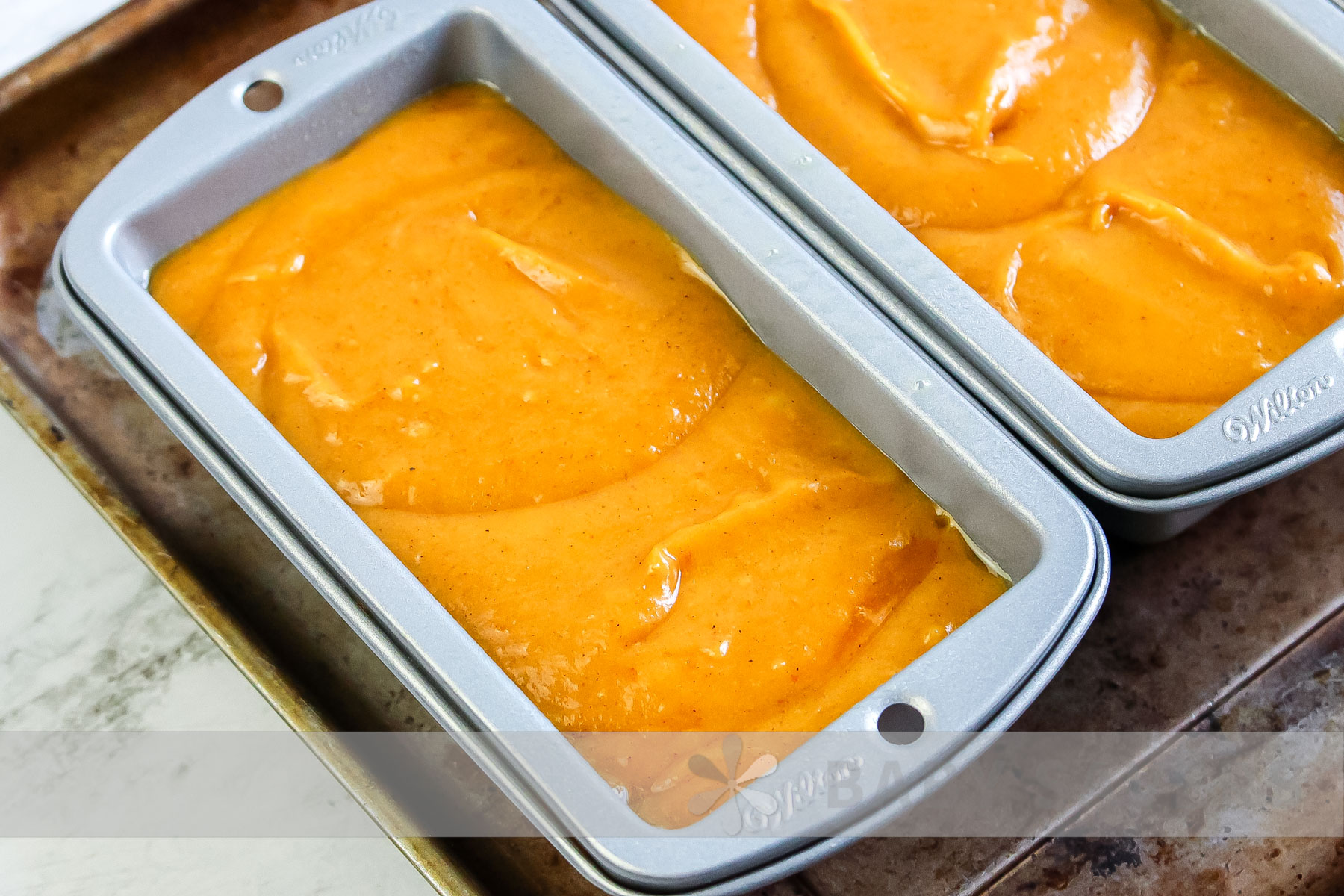 air fryer pumpkin bread before baking in two loaf pans on a baking sheet