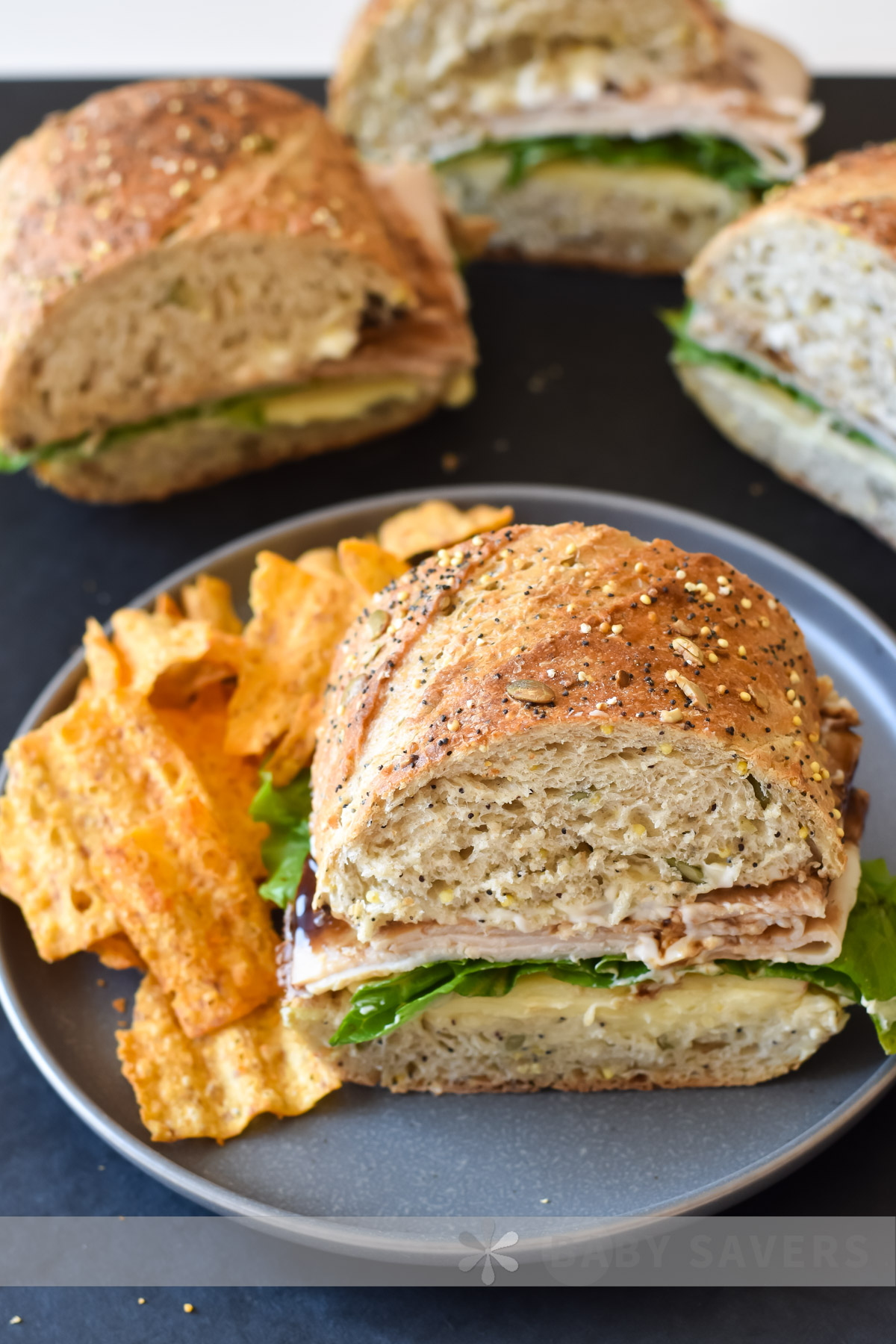 closeup image of the best turkey sandwich on a grey plate with orange chips alongside it