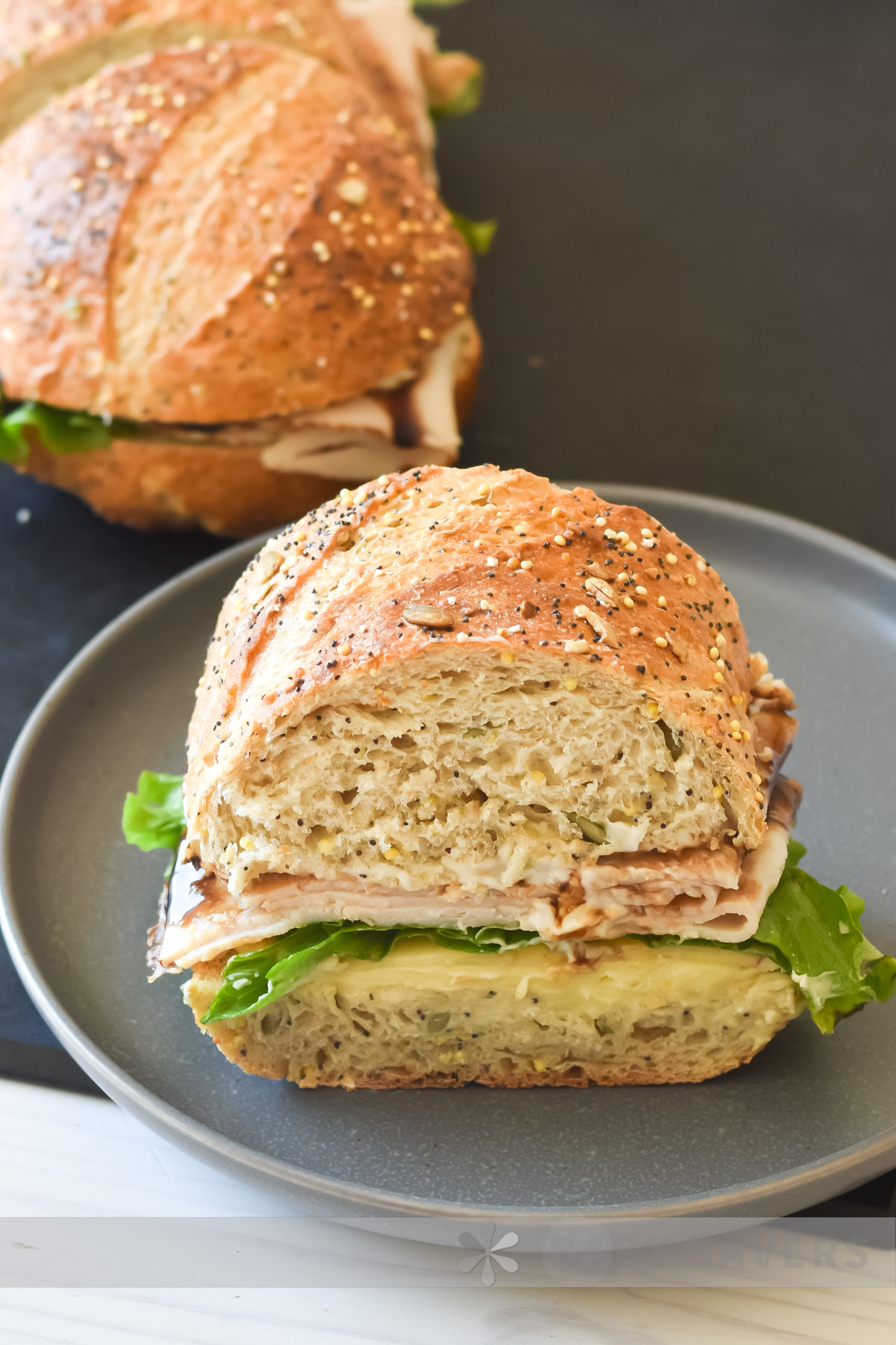 close up image of the best turkey sandwich on seeded bread with sliced turkey, brie cheese, lettuce, apples, mayonaise and balsamic glaze