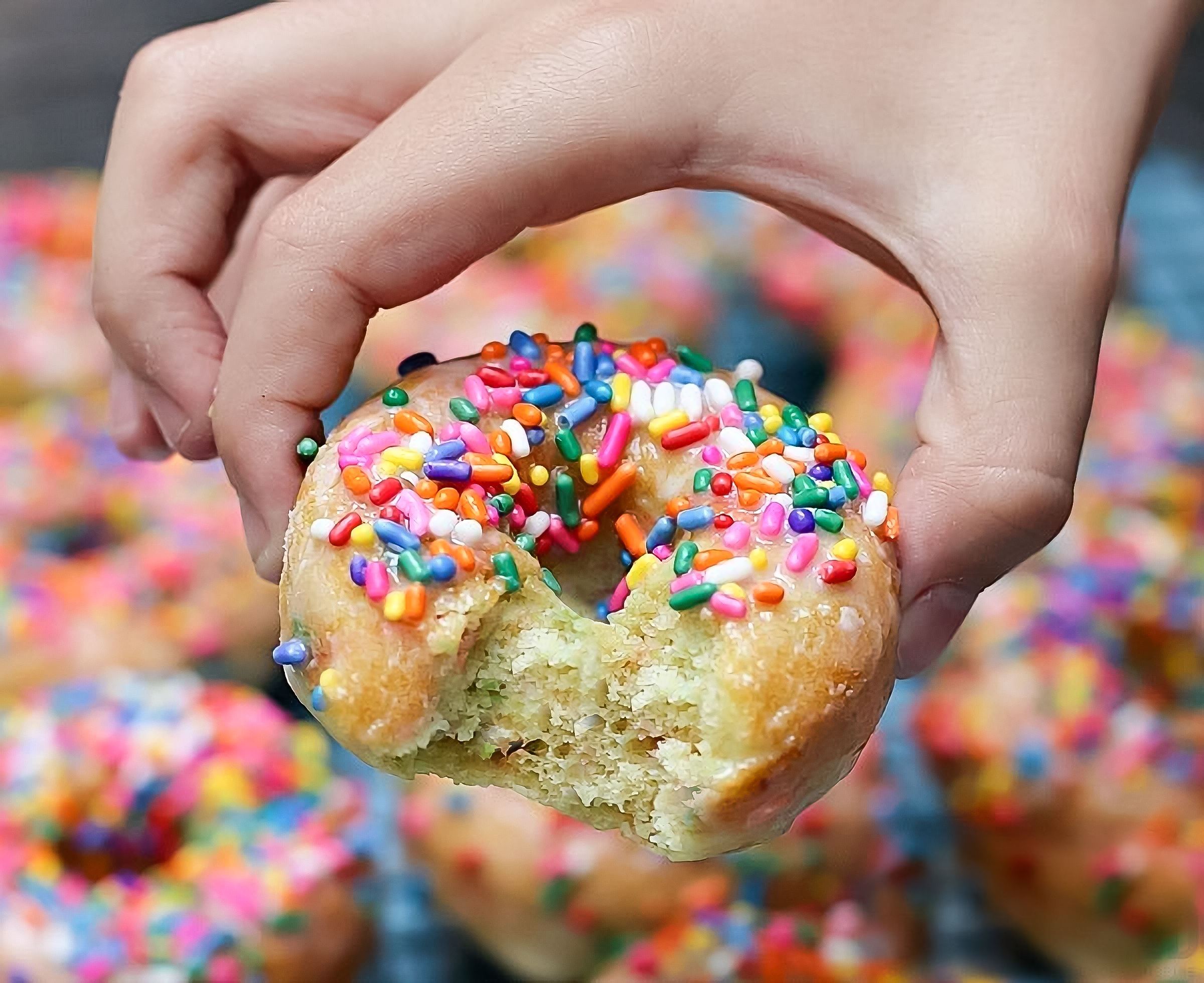 pancake mix donuts - hand holding a baked donut made with pancake mix topped with sprinkles