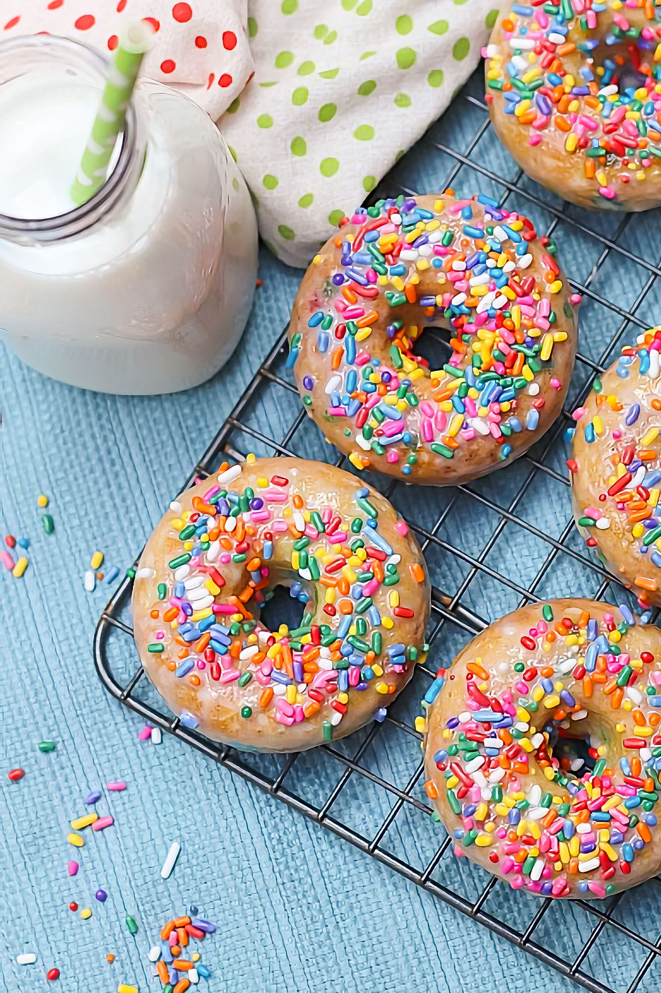 pancake mix donuts with rainbow sprinkles on a wire tray with a bottle of milk