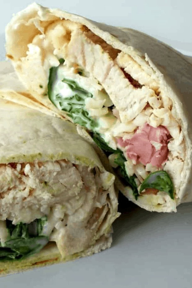A close-up image of a cut chicken wrap filled with slices of chicken, lettuce, mayonnaise, and ham, all wrapped in a soft, white tortilla. Perfect for busy families looking for
