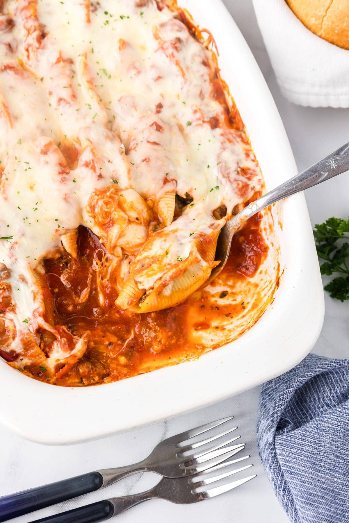A dish of baked pasta shells filled with cheese, covered in tomato sauce and melted mozzarella, served in a white casserole. This easy dinner idea is perfect for busy families. 