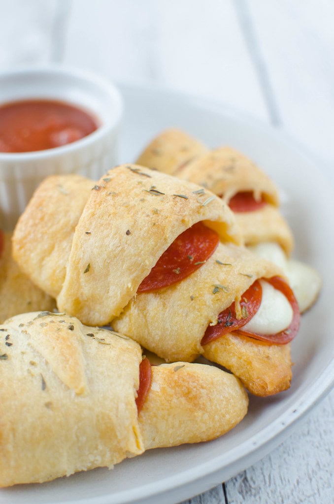 A plate of freshly baked pepperoni and cheese stuffed crescent rolls, perfect for easy dinner ideas, served with a side of marinara sauce for dipping, displayed on a wooden table.