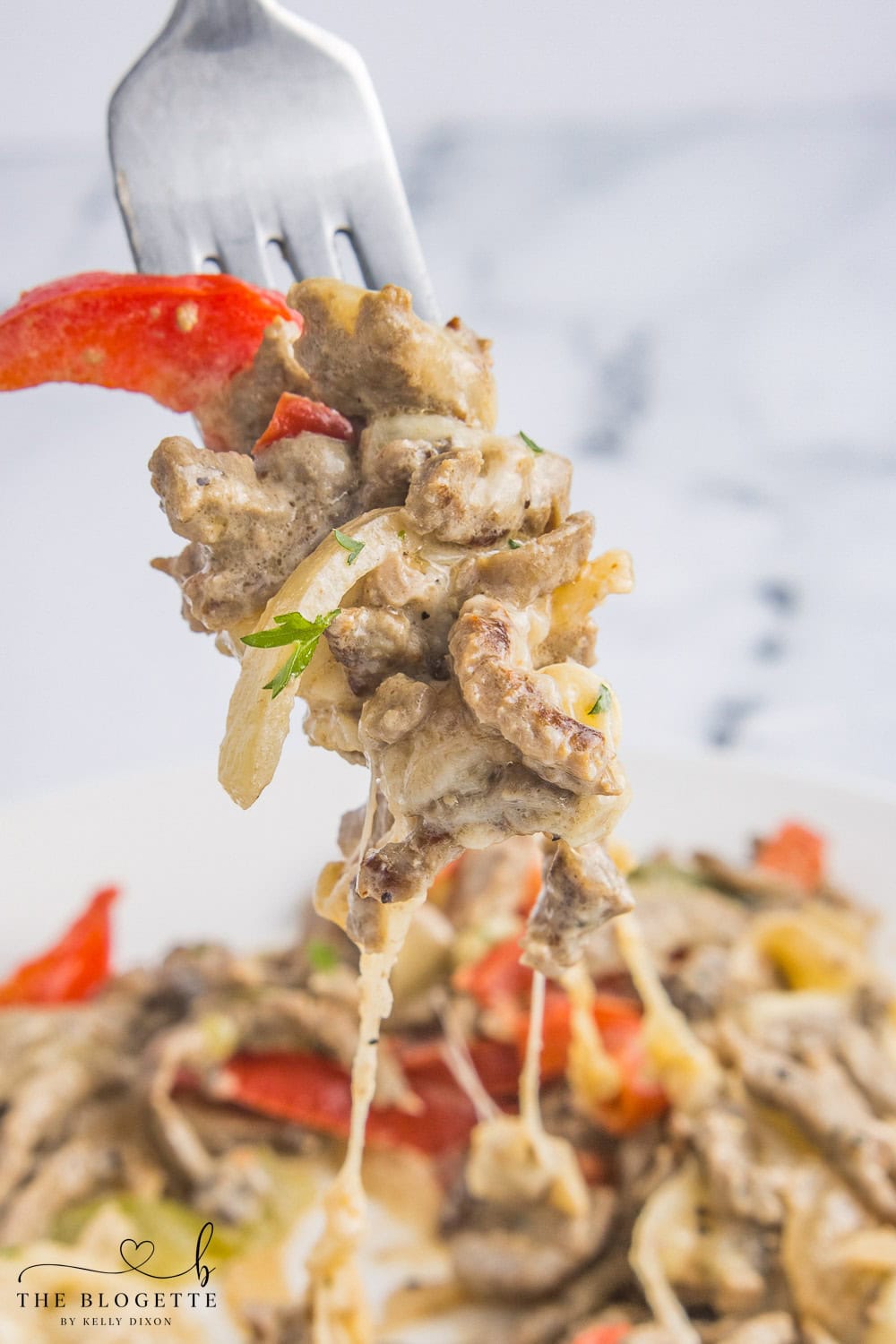 A silver fork  lifting a bite of philly cheesesteak casserole with peppers and melty cheese, perfect dinner idea for busy families.