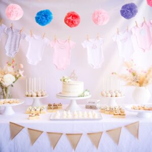 A baby shower table brimming with delightful ideas showcases a cake, cake pops, and pastries. Overhead, colorful pom-poms and charming baby onesies hang on a line. The table radiates joy with its floral accents and a cheerful triangular banner.