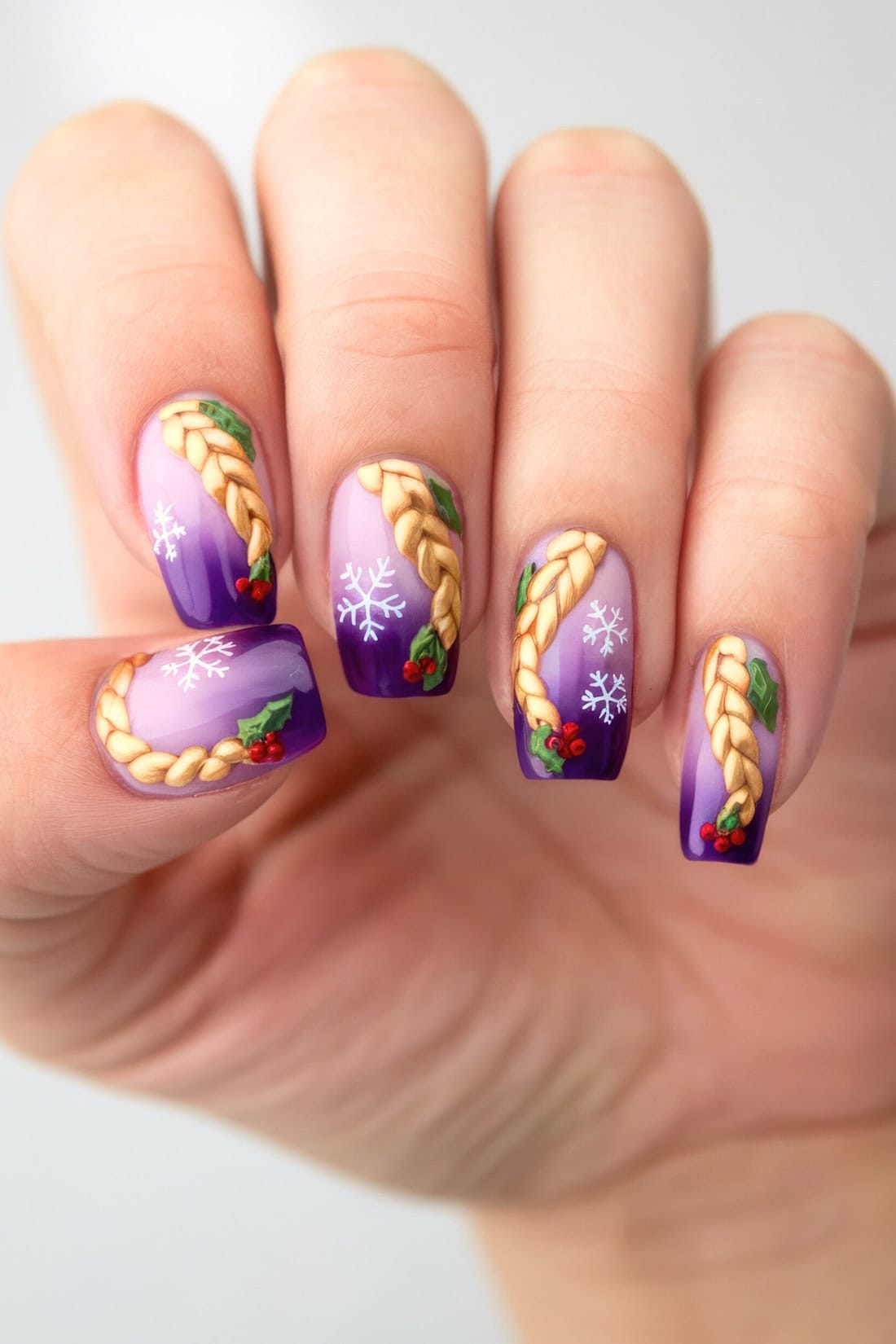 A hand with festive Disney-inspired nail art on purple polish. The nails feature braided golden strands, white snowflakes, green holly leaves, and red berries, creating a magical Christmas-themed design.