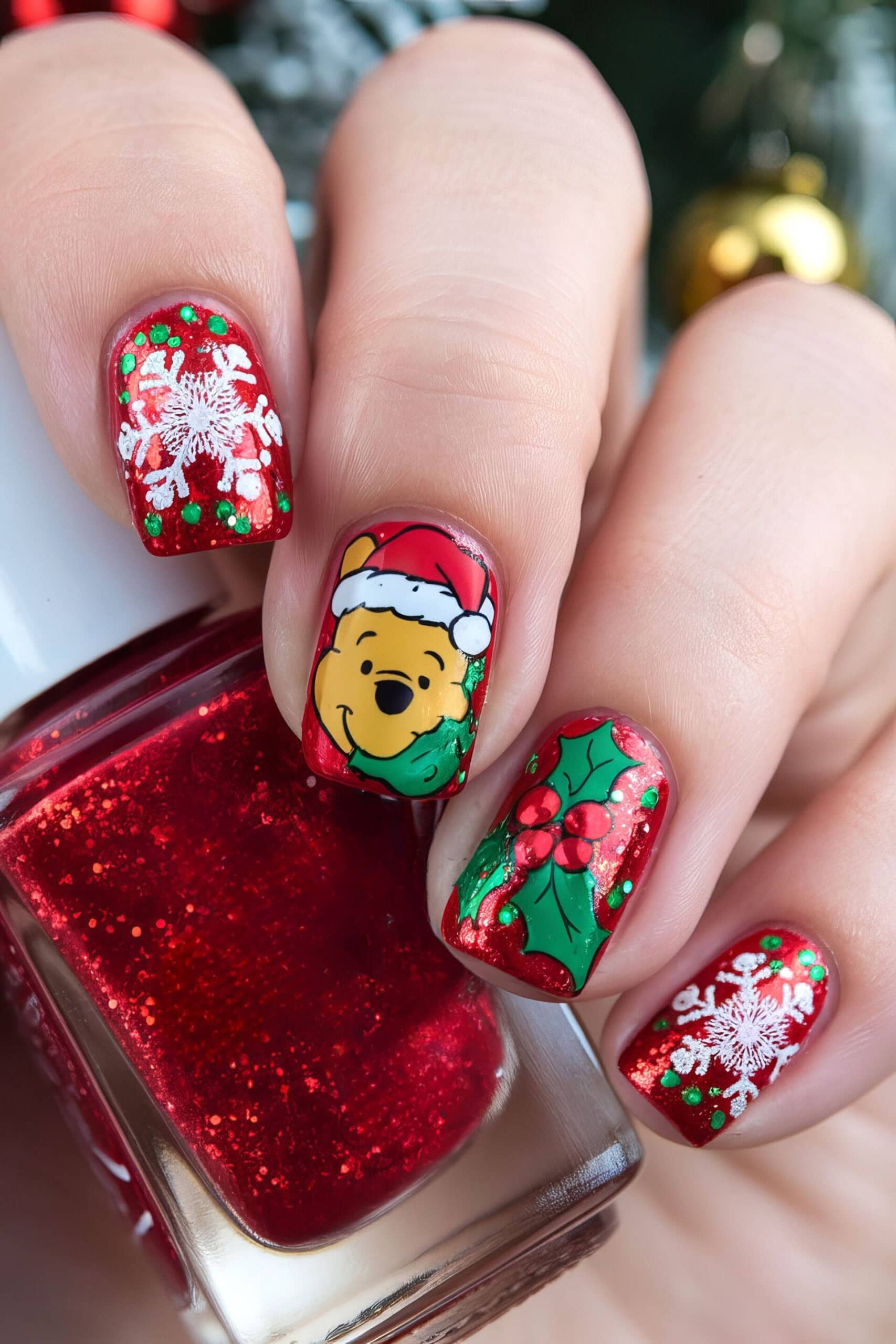 Close-up of festive nail art featuring a red and glittery polish. The center nail showcases a Winnie the Pooh bear wearing a Santa hat, reminiscent of Disney Christmas nails. Surrounding nails display snowflakes and holly leaves with berries, adding a whimsical holiday theme.