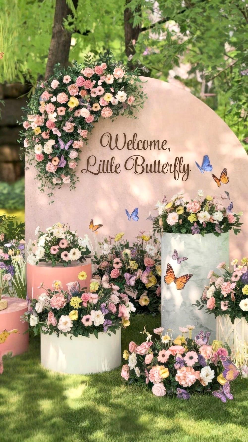 A garden scene with a sign reading "Welcome, Little Butterfly" offers enchanting butterfly baby shower ideas. Adorned with colorful flowers, butterflies dance around pastel flower arrangements on pink and white platforms, while lush greenery completes the serene setting.