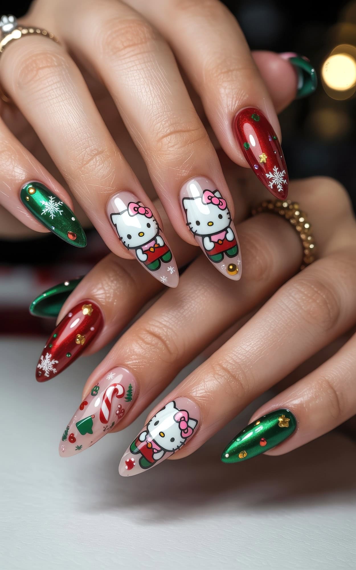 Hands with long, almond-shaped nails feature festive Christmas-themed nail art, including red and green polish, snowflakes, candy canes, and cute Hello Kitty Christmas nails with cartoon cat designs in Santa outfits.